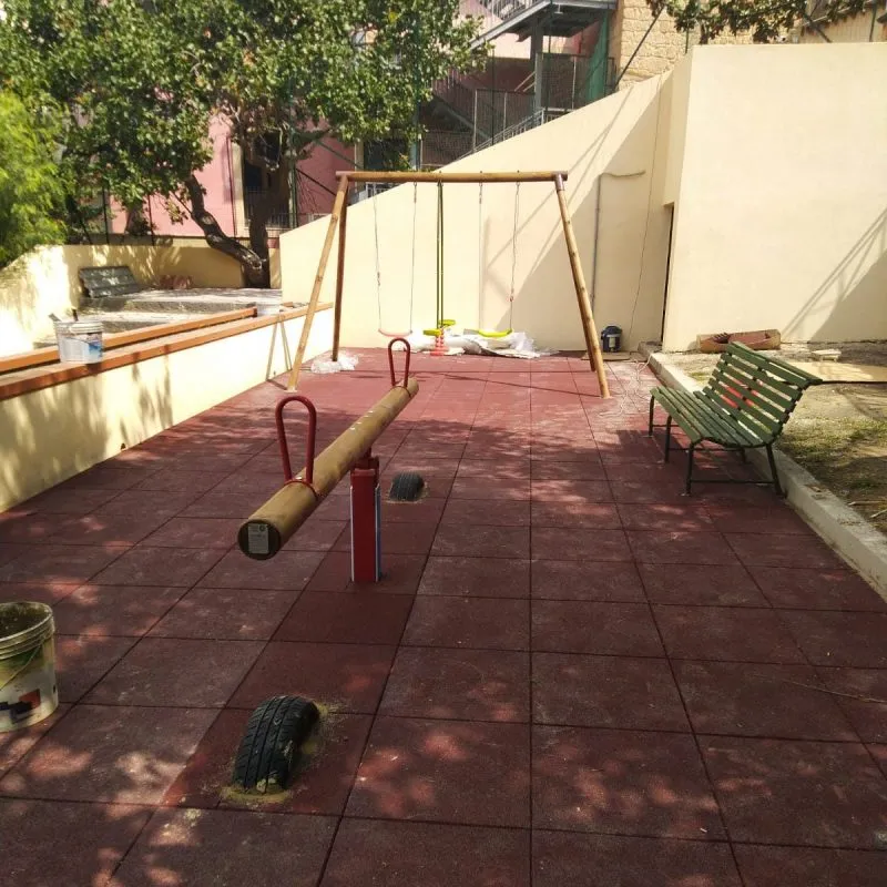 Cortile privato con altalene e pavimentazione antitrauma BePlay rossa